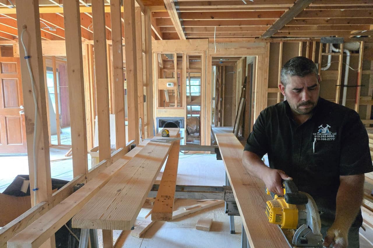 The owner of Top Line Remodel cutting framing stock with a circular saw inside a house opened up to bare studs